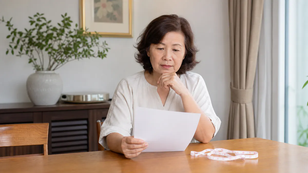 Malaysian Chinese woman reviewing a health checklist and measuring tape.