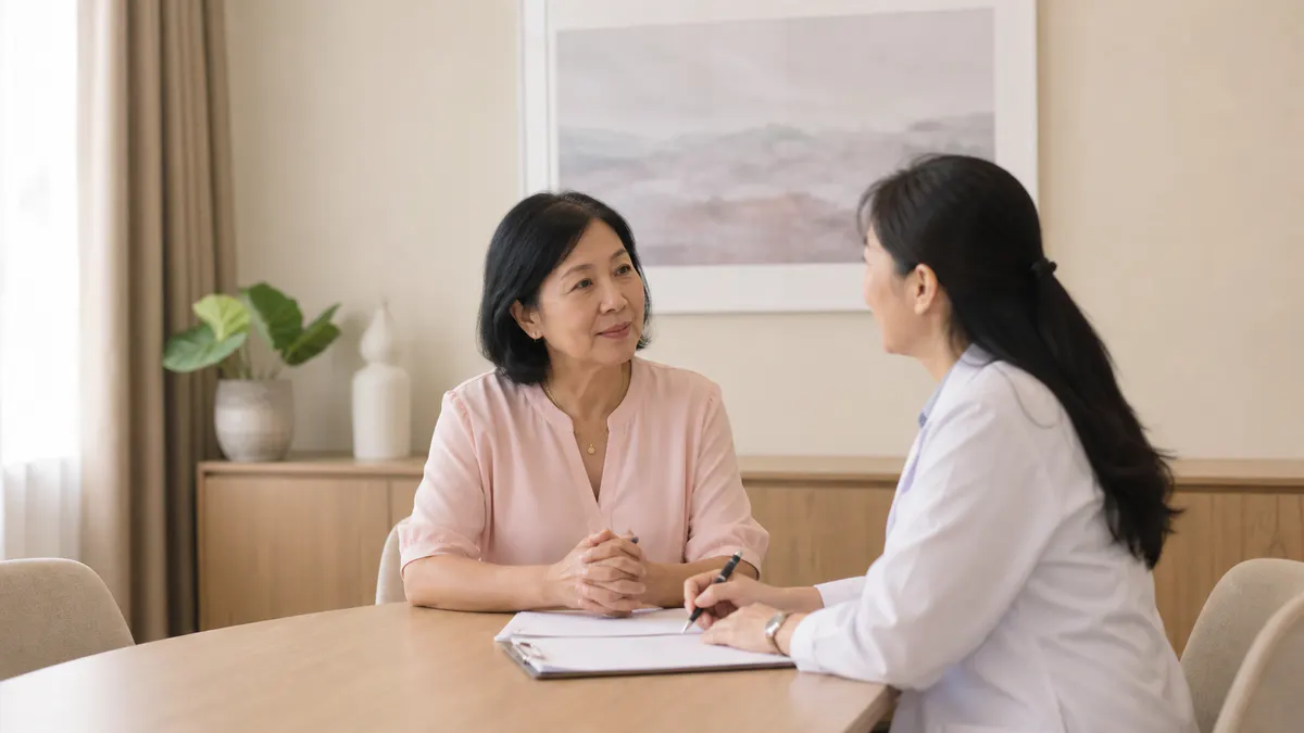 Malaysian Chinese woman speaking with a female clinician in a consultation room.