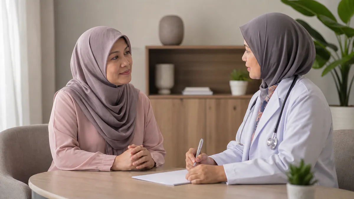 Wanita Melayu berbincang dengan doktor wanita di bilik konsultasi.
